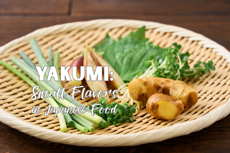 Cover image featuring a selection of traditional Japanese yakumi (aromatic condiments), including ginger, shiso leaves, myoga, green onions, and kaiware sprouts, arranged on a woven bamboo tray. The title introduces yakumi as the small yet essential flavors that bring freshness, aroma, and balance to Japanese food.